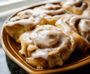 Delicious homemade apple cinnamon rolls topped with icing, showcasing a soft, flaky pastry filled with cinnamon-spiced apple filling and a sweet glaze.