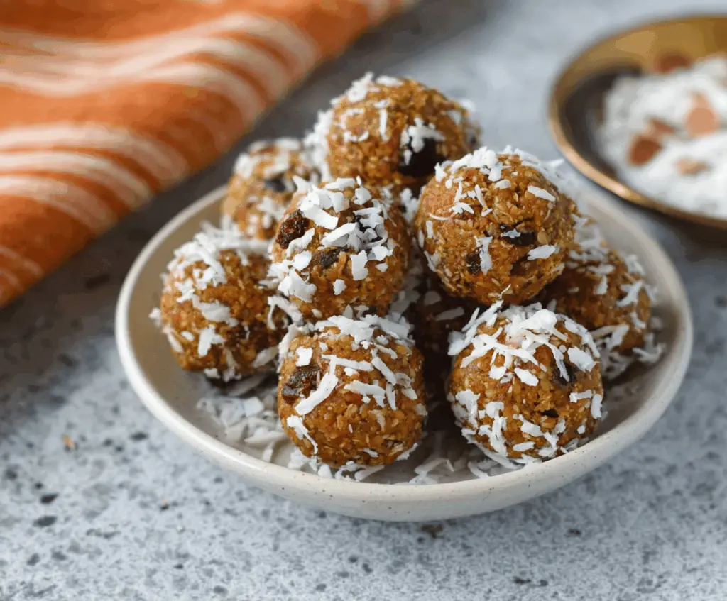 Healthy pumpkin coconut energy balls on a white plate, featuring a festive fall flavor with pumpkin, coconut, and seeds, perfect for a nutritious snack.
