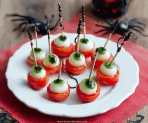 Colorful Eyeball Caprese Skewers with cherry tomatoes, mozzarella balls, fresh basil, and black olive pupils for a spooky Halloween appetizer.